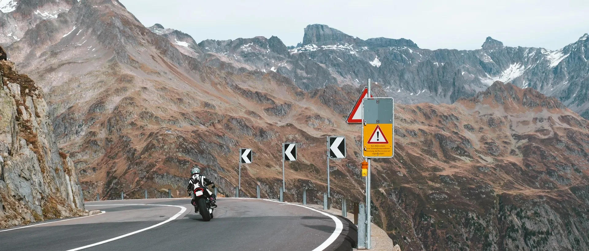 Dağ yolunun virajında koruyucu ekipmanlı motosiklet sürücüsü